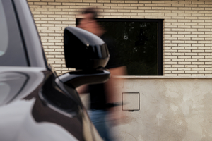 Man wandelt langs een zwarte wagen en een Sotto Murra Integrated laadpunt in een gecementeerde muur