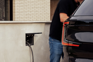 Man koppelt de laadkabel aan zijn zwarte wagen via een Sotto Murra Integrated laadpunt met geopende klep