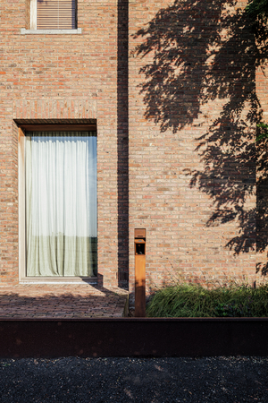 Cortenstalen Sotto Terra laadpunt voor de bakstenen gevel van een villa