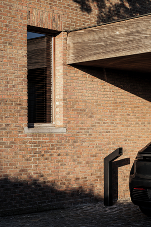 Zwart Sotto Terra laadpunt naast een wagen aan de bakstenen gevel van een villa